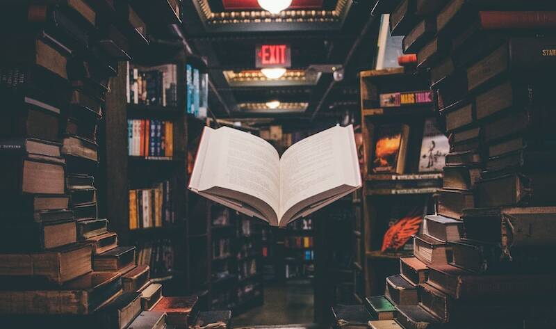 view of floating open book from stacked books in library