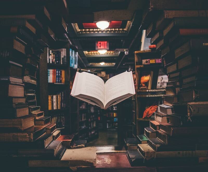 view of floating open book from stacked books in library